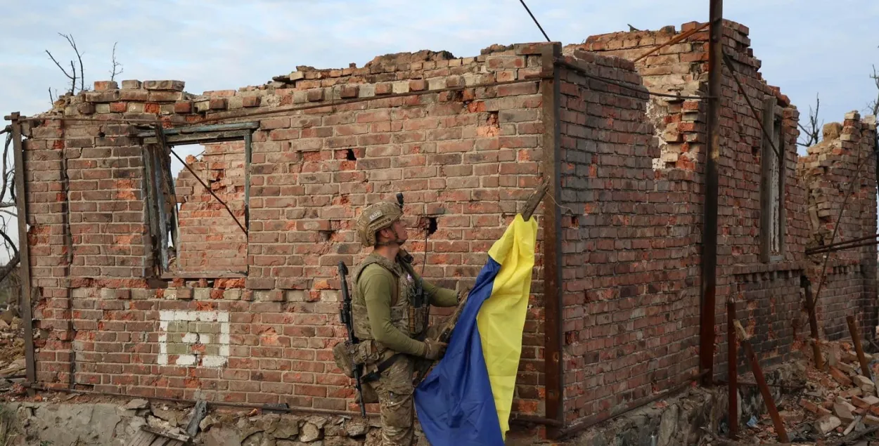 Украінскі вайсковец усталёўвае дзяржаўны сцяг у вызваленым населеным пункце пад Бахмутам